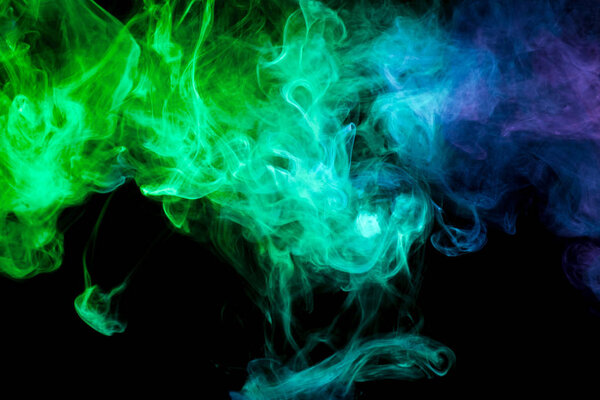 Thick blue and green colorful smoke on a black isolated background. Background from the smoke of vap
