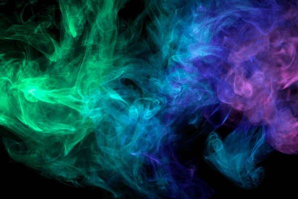 Thick purple, green and blue colorful smoke on a black isolated background. Background from the smoke of vap
