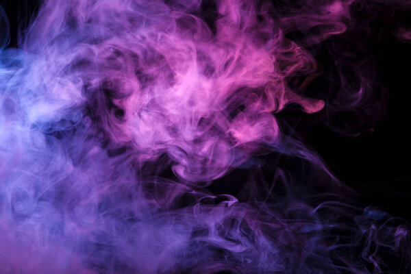Thick colorful smoke of pink, purple blue on a black isolated background. Background from the smoke of vap