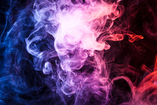 Thick colorful smoke of pink, orange, blue on a black isolated background. Background from the smoke of vap