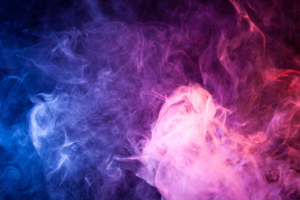 Dense multicolored smoke of pink,  blue and purple colors on a black isolated background. Background of smoke vap