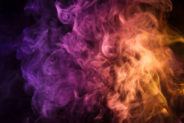 Yellow  and pink  cloud of smoke of  black isolated background. Background from the smoke of vap