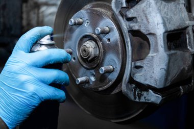 Yakın plan atölye çalışanı koruyucu eldivenlerle tekerlek çivilerini yağlıyor, fren tamiri yapıyor. Lastik atölyesinde çalışıyorum.