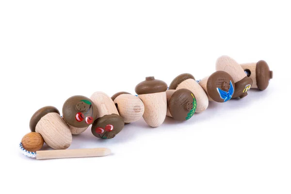 A close-up of children\'s toys made of natural wood in the form of acorns with shells, painted with different patterns - butterflies, flowers, bees. Eco-friendly toy for parents and children