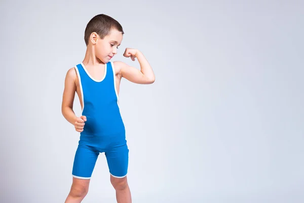 青いレスリングのタイツ姿の明るい男の子の肖像画は 彼を自信を持って見て 白い孤立した背景にポーズをとっています 小さな戦闘機の選手の概念 — ストック写真