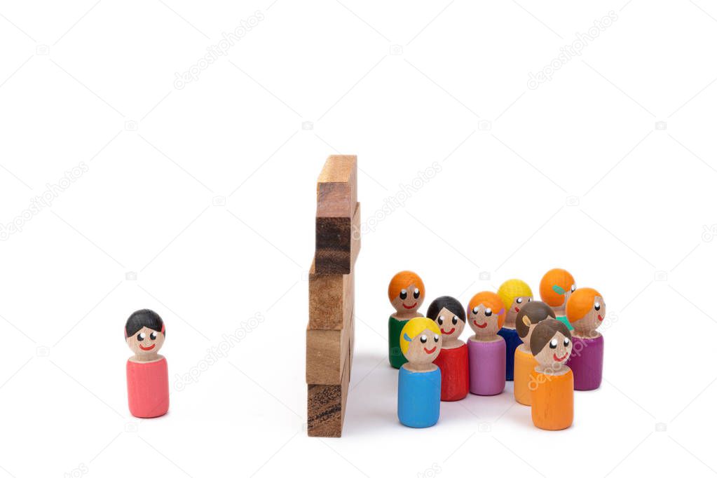 A team of wooden toys and a lonely woman are separated by a high wall. The image of the separation of families by dictatorial methods. The concept of lonely life.