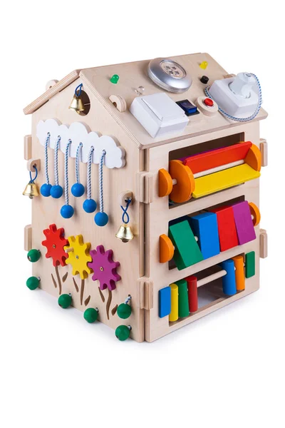 Wooden  busy board house - educational toy for children, babies on a white isolated background, consisting of multi-colored wooden flower puzzle pieces, bells, gear, sorter, switches, lamp