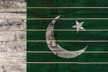 Tahta duvarda Pakistan bayrağı var. Ulusal gurur kavramı ve ülkenin bir sembolü. Ahşap bir çitin üzerine bir iple bayraklar boyanmış.