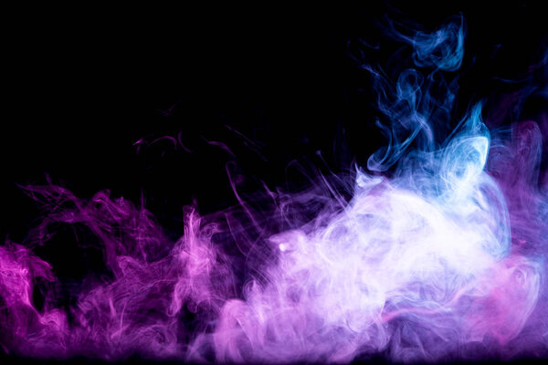 Fog colored with bright pink gel on dark background.Frozen abstract movement of explosion smoke multiple colors on black background.