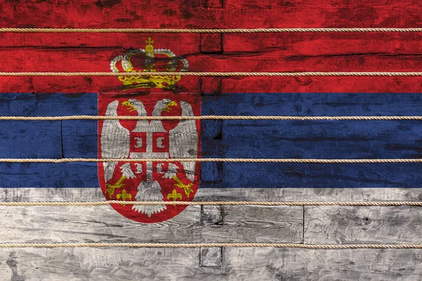 木製の壁の背景にセルビアの国旗 国家の誇りと国のシンボルの概念 ロープで木製の柵に描かれた旗 — ストック写真