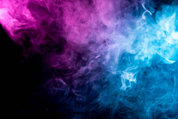 Close up swirling pink and blue smoke on black isolated background. Colorful cloud of smoke