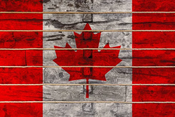 National flag  of Canada on a wooden wall background. The concept of national pride and a symbol of the country. Flags painted on a wooden fence with a rope