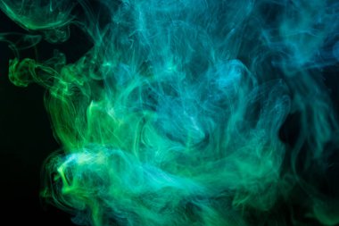 Soyut sanat mavi ve yeşil renkli duman siyah izole arka planda. Koyu renkli dumanların hareket etmesini durdurun.