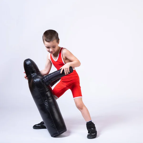 Cheerful sport boy in wrestling tights and wrestlers makes a throw through the back with a sporting dummy for training and handling techniques from various martial arts on a spruce isolated background