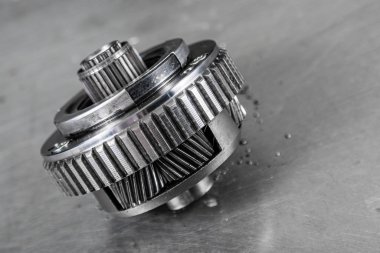 Bir araba şanzımanının önemli bir yedek parçasının yakın plan görüntüsü. Gezegen vites kutusu için parlak metal teçhizat. Metal ototeknoloji arka planı, içinde dişliler olan gümüş metaller..