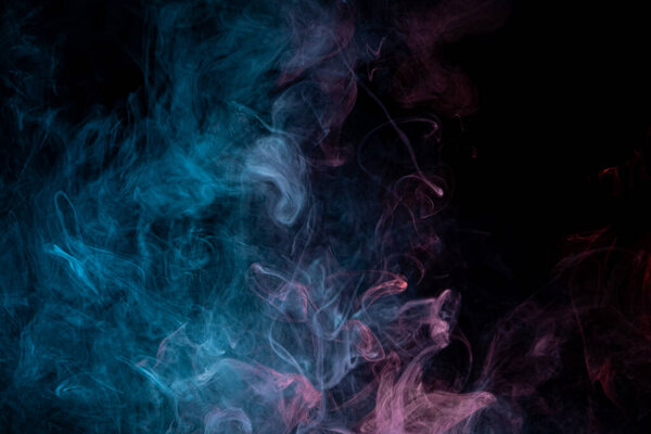 Thick colorful smoke of red, blue on a black isolated background. Background from the smoke of vape