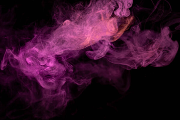 Thick colorful smoke of red and pink on a black isolated background. Background from the smoke of vape