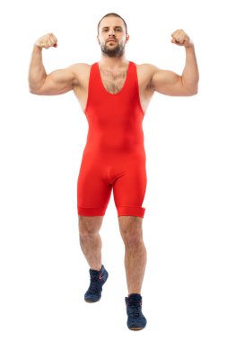 Strong strong young man in a sports red tights stands showing biceps, looking confidently forward on a white isolated background. Concept of athlete, Greco-Roman wrestler for sports design. clipart