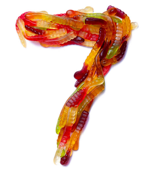 Arabic numeral "7"  from multi-colored chewing marmalade on a white isolated background. Food pattern made from children's sweets snakes. Bright alphabet for kids design