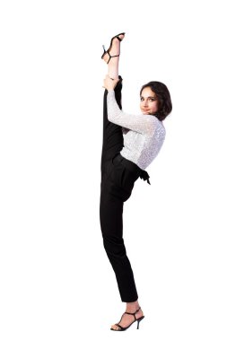 Güzel bluzlu, parlak makyajlı, çekici bir kadın. Işıltılı, siyah pantolonlu ve sandaletli. Beyaz, izole bir arka planda bacağını başının üstüne uzattı. Kadın jimnastiği, her yerde mükemmel bir esneme ve sicim gösterisi.