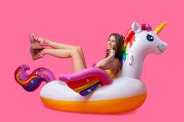 Yaz moda güzel kadın yaz giysileri eğlenmek, gülümseme ve balon ile poz üzerinde Unicorn float izole pembe arka plan