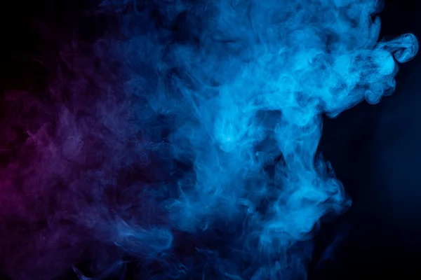 在黑色的背景上以神秘而神奇的形式将五彩斑斓的蓝色和粉色蒸汽烟熏在一起 — 图库照片