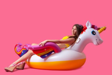 Yaz moda güzel kadın yaz giysileri eğlenmek, gülümseme ve balon ile poz üzerinde Unicorn float izole pembe arka plan