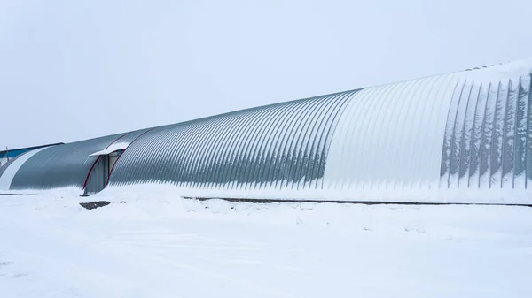 A large metal industrial warehouse for storing goods in winter day. Industrial concept of transportation, loading and storage of goods