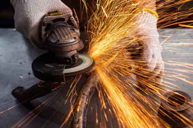Bir genç adam kaynakçı bir mavi eldiven değirmeni bir açı değirmeni atölyede metal, sinek tarafa kıvılcım