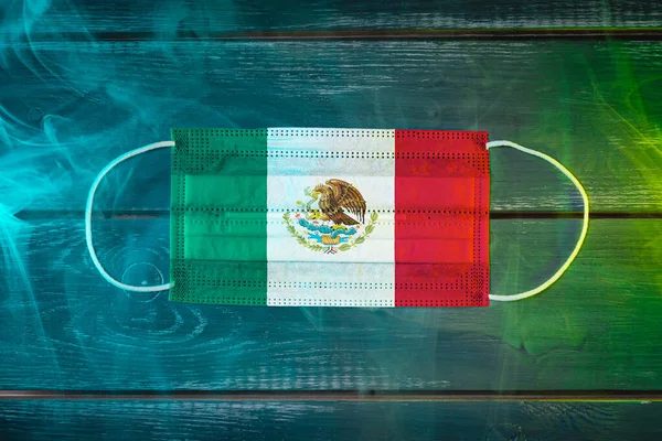 青い緑色の煙の中で黒い背景にメキシコの国旗に描かれた 航空疾患に対する保護のための医療用マスク 空気感染症 コロナウイルスに対する医療保護 — ストック写真