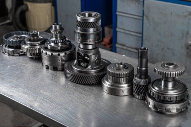 Çeşitli motor ve yedek şanzıman parçaları seti. Gezegen şanzımanı için parlak vitesler. Metal ototeknoloji arka planı. Tekerlek motoru dişlileri, kapatın.