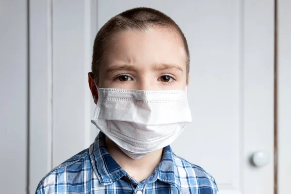 Young boy with sore eyes in a medical mask look at camera. Medical protection against airborne diseases, coronavirus. hild is afraid of getting the flu
