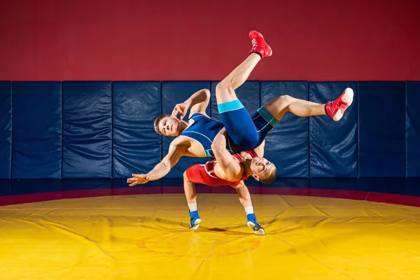 파란색 유니폼을 레슬링을 그리스 체육관에서 노란색 레슬링 카펫에서 레슬링을 있습니다 — 스톡 사진