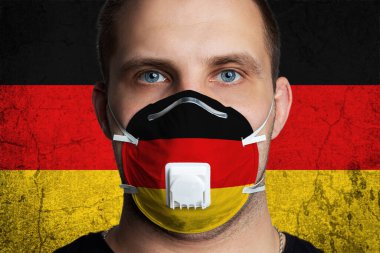 Almanya bayrağının renklerine boyanmış, yaralı gözlü, tıbbi maskeli genç bir adam. Coronovirus hastalığı COVID-19 konsepti. Adam grip olmaktan korkuyor.