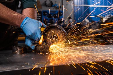 Genç bir kaynakçı metal, atölyede bir üçkağıtçı, kıvılcımlar uçuşuyor. Fabrikada metalle çalışan kaynakçı.