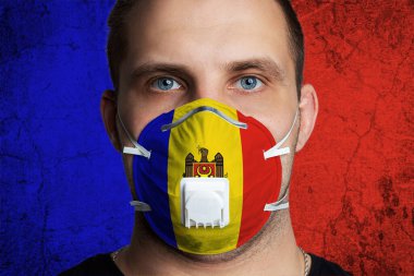 Tıbbi maske takmış, Moldova bayrağının renklerine boyanmış yaralı gözleri olan genç bir adam. Coronovirus hastalığı COVID-19 konsepti. Adam grip olmaktan korkuyor.