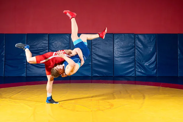 公正なレスリングの概念 ジムで黄色のレスリングカーペットの上で赤と青の均一なレスリングで2人のグレコ ローマの力士 — ストック写真