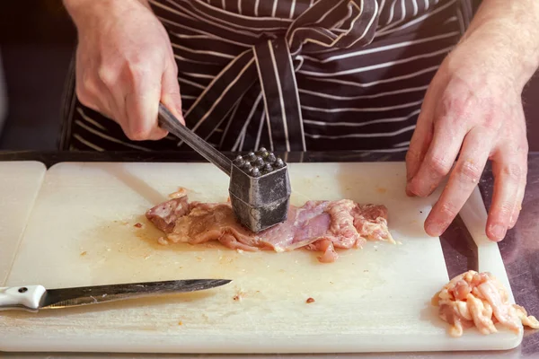 걸음씩 요리를 하는데 앞치마를 이나무 널빤지 망치로 부순다 부드러운 고기를 — 스톡 사진