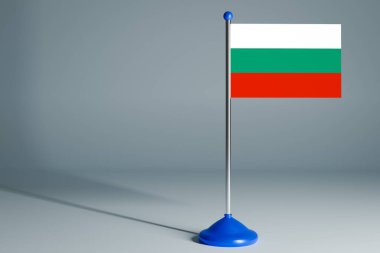 Bulgaristan 'ın 3D gerçekçi ulusal bayrağını gri izole arka planda çelik direğe asıyor. Boş masa bayrağı, tasarım için uygun, alaycı