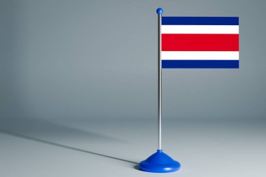 Kosta Rika 'nın 3D gerçekçi ulusal bayrağını gri izole arka planda çelik direğe asıyor. Boş masa bayrağı, tasarım için uygun, alaycı