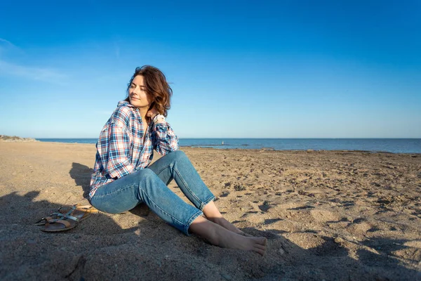 Radosna Ciemnowłosa Kobieta Uśmiecha Się Siedząc Plaży Cieszy Się Jasnym — Zdjęcie stockowe