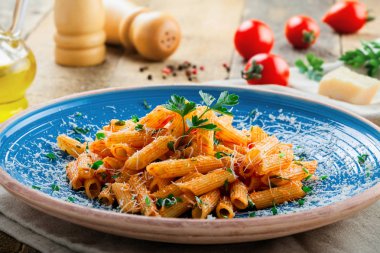 İtalyan penne makarna arrabiata domates sosu ve rustik mavi tabakta maydanoz ile. Geleneksel İtalyan mutfağının sağlıklı. Yakın çekim vurdu.