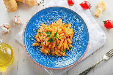 Geleneksel İtalyan penne makarna mavi rustik tabakta arrabiata domates soslu. Lezzetli sağlıklı Akdeniz mutfağından yemekler. Üstten Görünüm.