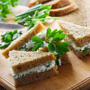 Çavdar ekmeği, krem peynir, taze maydanoz ve yeşil soğan bir tabloda küçük sandviç yaptı. Basit ev yapımı snack. 