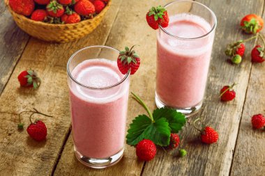 Rustik ahşap bir masa üzerinde taze olgun çilek milkshake yapılmış. Sağlıklı kahvaltı sağlıklı meyve içmeye.
