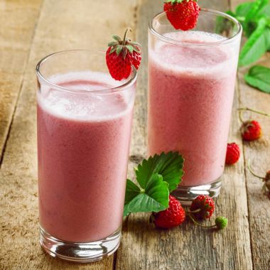 Ahşap bir masa üzerinde taze çilekli milkshake. Sağlıklı meyve güler yüzlü içki.