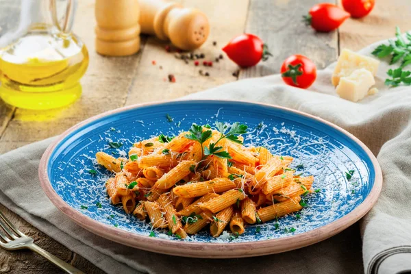 İtalyan penne makarna arrabiata domates sosu ve rustik mavi tabakta maydanoz ile. Geleneksel İtalyan sağlıklı mutfağı.