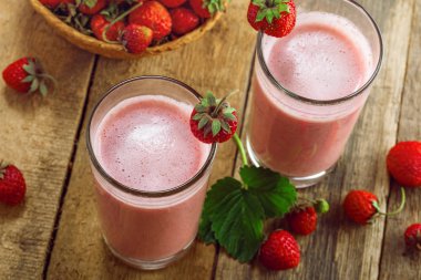 Rustik bir tabloda sağlıklı çilekli milkshake. Lezzetli meyve sağlıklı yaşam tarzı için iç. Üstten Görünüm vurdu.