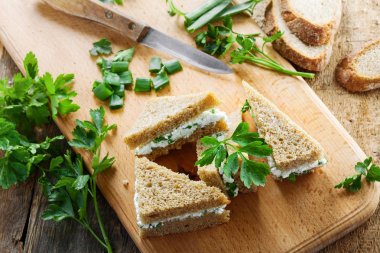 Çavdar ekmeği, krem peynir, taze maydanoz ve yeşil soğan bir tabloda basit sağlıklı snack yapılmış. Lezzetli küçük sandviçler. Üstten Görünüm.