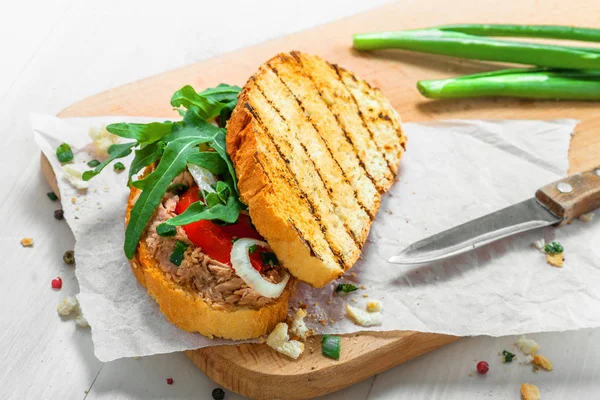 Classic tuna salad sandwich with tomato, onion and arugula on a white table. Delicious healthy meal made of fish, vegetables and toasts.